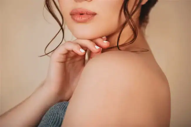 A woman posing with full lips, her hand under her chin.
