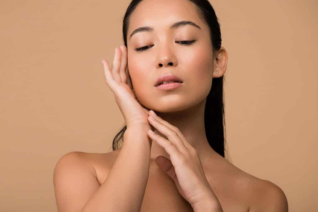 A woman posing with her eyes closed and hands on her face.