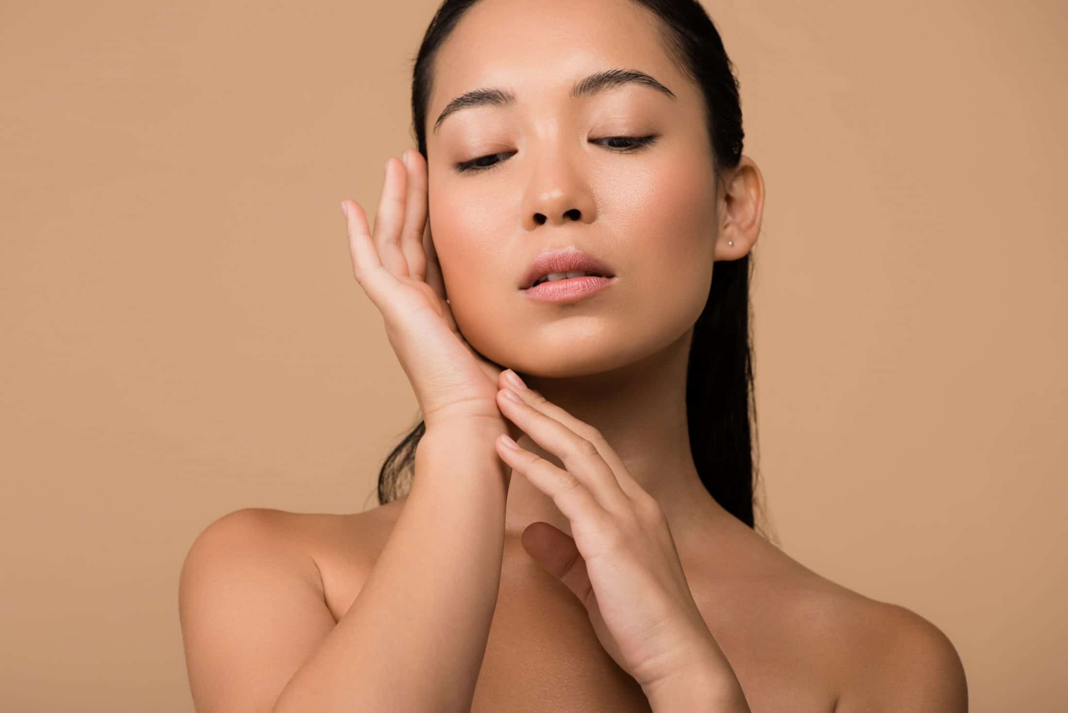 A woman posing with her eyes closed and hands on her face.