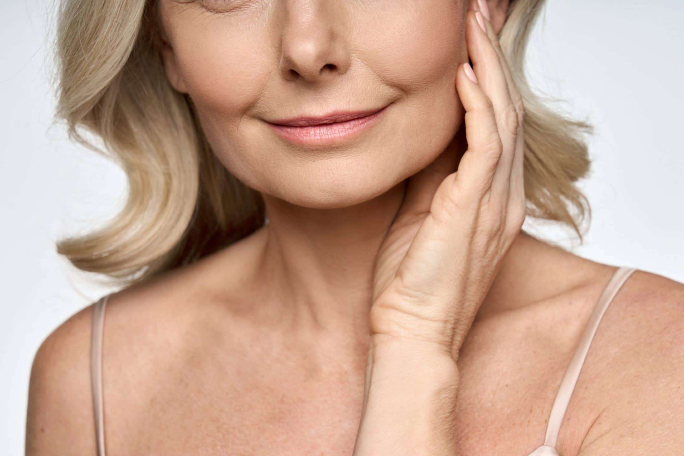 A woman in Scottsdale, Arizona smiling with one hand on her face after receiving Sculptra