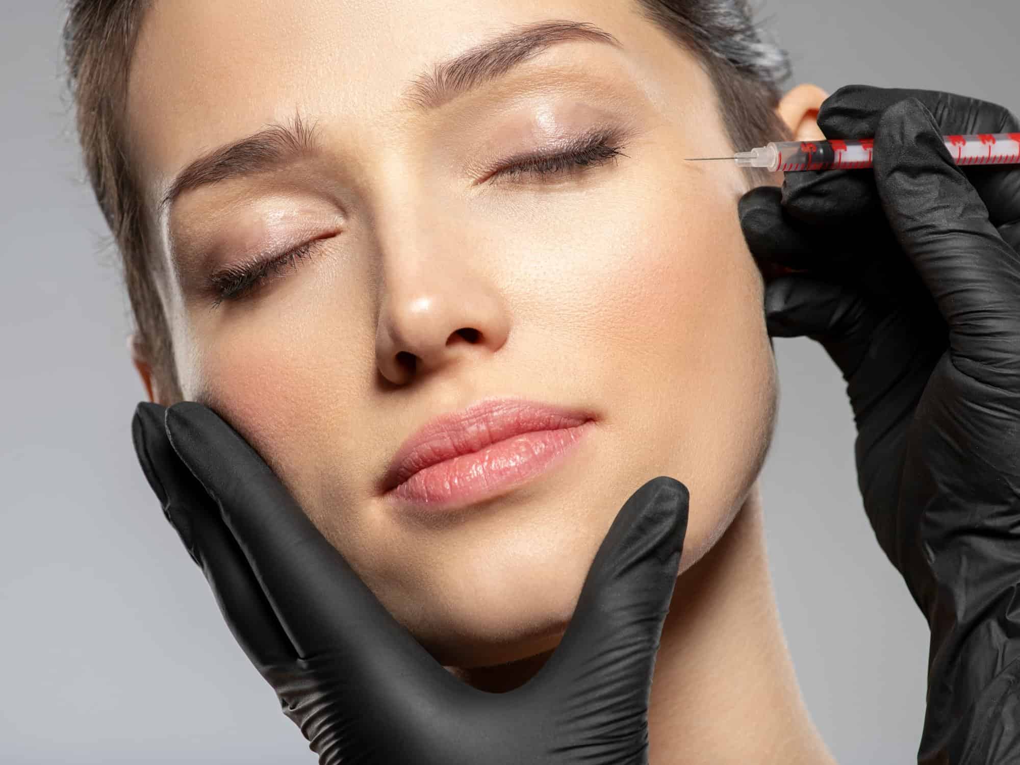 Caucasian woman getting botox cosmetic injection in forehead. Woman gets botox injection in her face