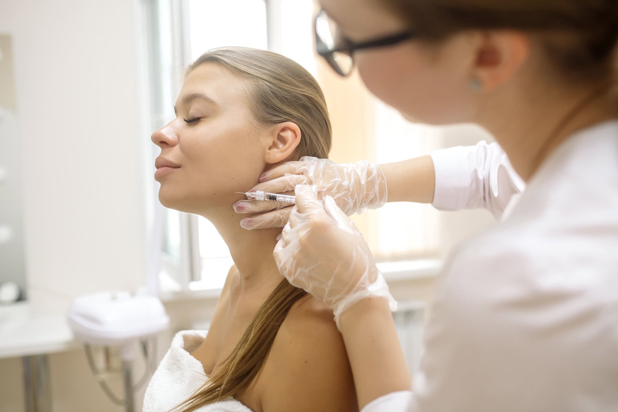 The cosmetologist makes injections to correct the angles of the lower jaw with a filler
