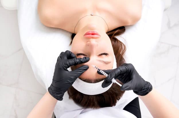Cosmetic expert giving a woman botox on her forehead