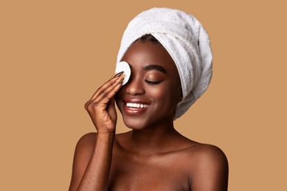 Woman cleansing her skin with a cotton pad.