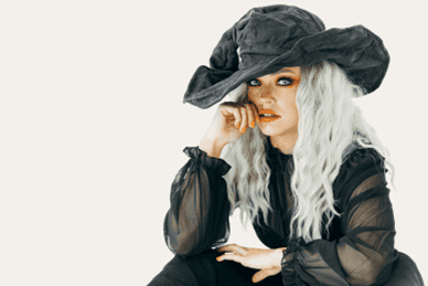 Image of a woman dressed as a witch wearing bright orange Halloween makeup.