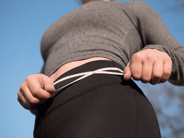 Image of a woman holding a measuring tape to her waist after Semaglutide treatment.